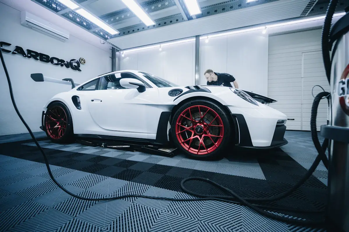 a white sports car with red rims in a garage